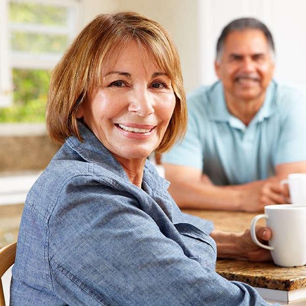 An older couple sitting at the table drinking coffee and smiling