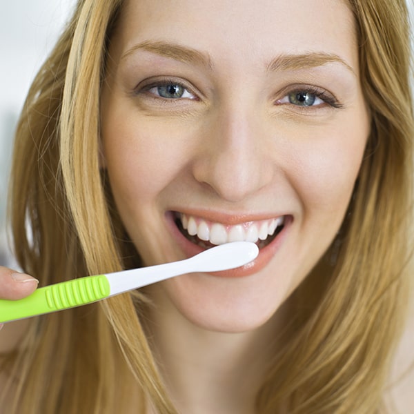A young woman brushing her teeth while smiling