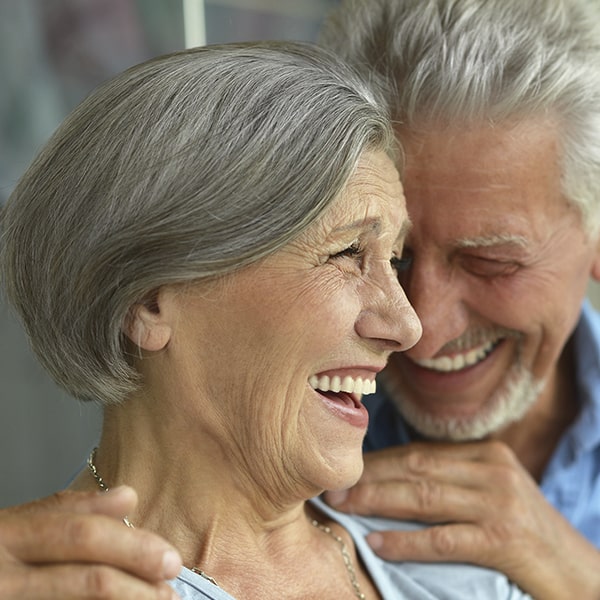 An older couple smiling as they hug